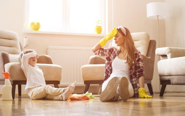 Mother and a daughter feeling exhausted after cleaning home together